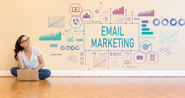 A girl with laptop sitting on the floor, the background wall displays Email Marketing and various icons and charts