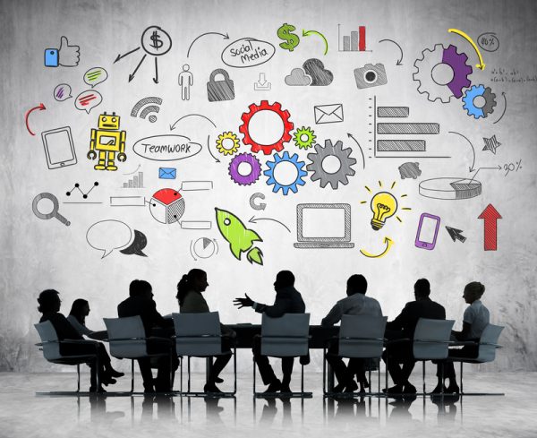 A conference room meeting with people discussing software design and user experience elements portrayed in the backdrop