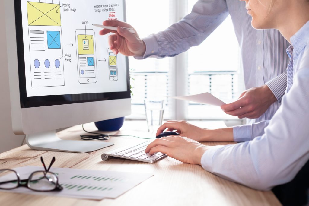 2 people discussing an E-commerce website design layout that is displayed on the computer screen