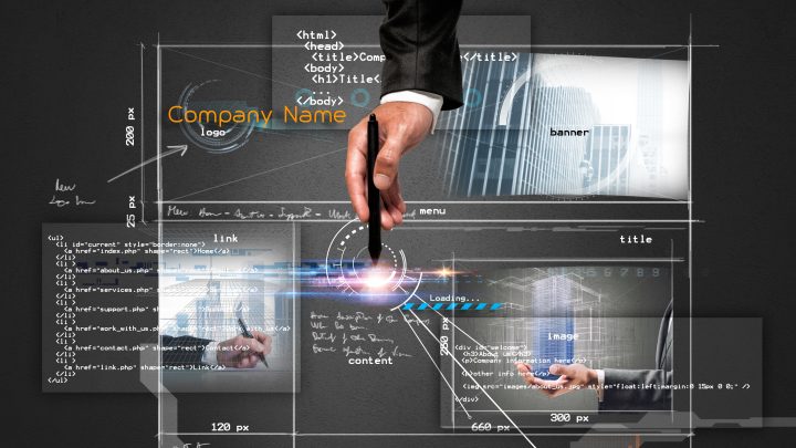A hand with a pen pointing towards a computer screen that shows coding for website development