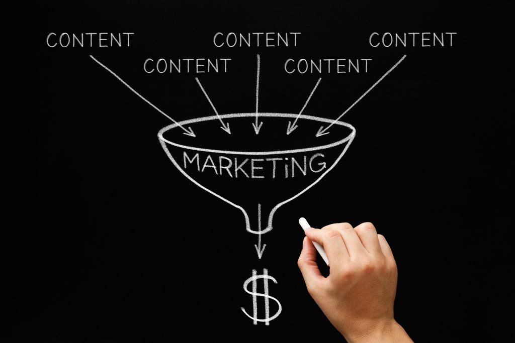 A hand with a chalk creating a chart on a blackboard that portrays the role of content marketing strategy services