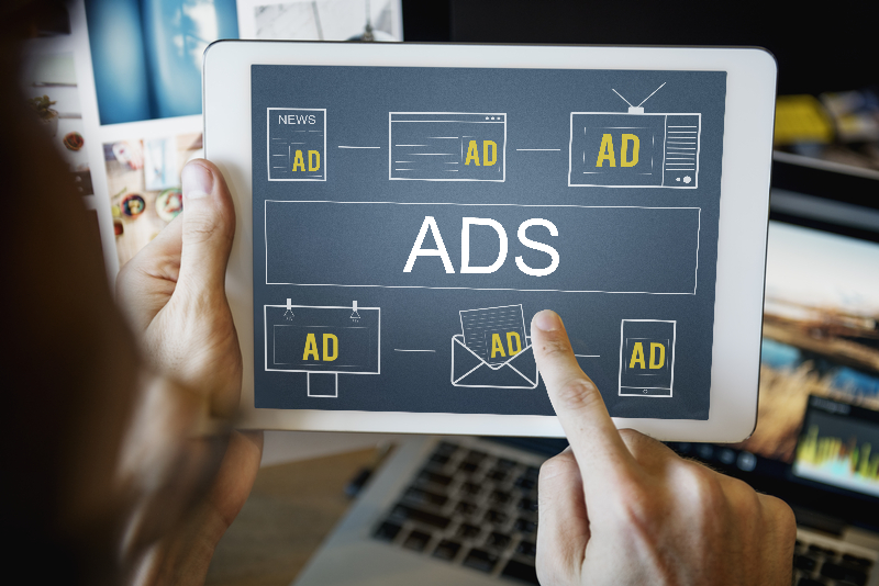 Display AD specialist holding a digital tablet. Screen shows different formats of Display ADs.